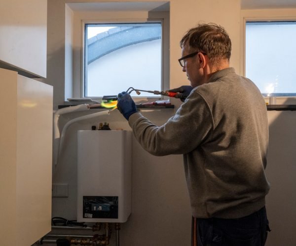 A handyman meticulously works on repairing a boiler.