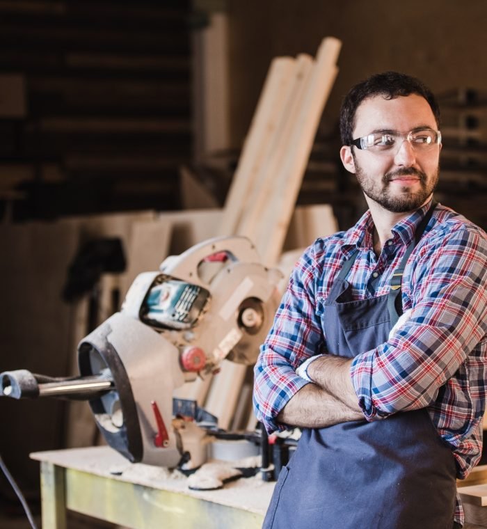 Happy young handyman carpenter in workshop, smiling Happy young handyman carpenter in workshop, smiling