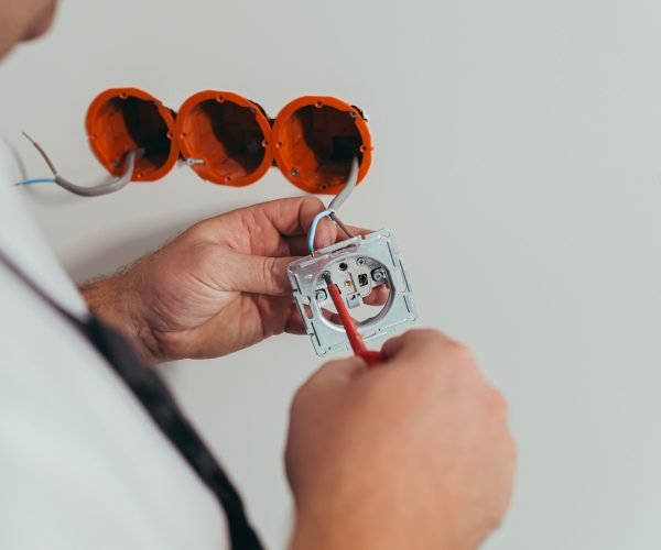 Male worker professional electrician mounts an electrical outlet in the apartment after repair Male worker professional electrician mounts an electrical outlet in the apartment after repair