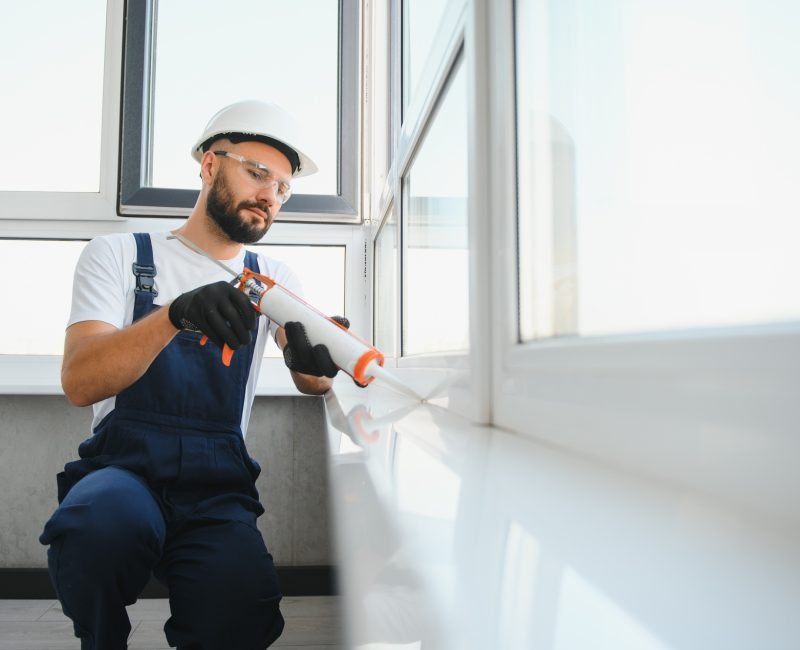 Young man, dressed in a uniform, doing repair in the house. Handyman